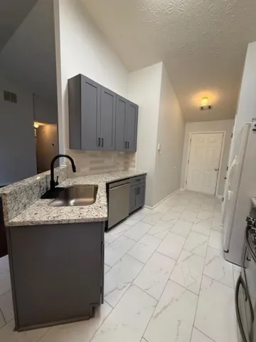 a kitchen with granite countertop a sink a stove and cabinets