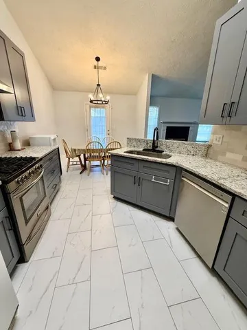 a kitchen with stainless steel appliances granite countertop a sink stove and cabinets
