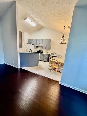 a view of a kitchen with kitchen island wooden floors and stainless steel appliances