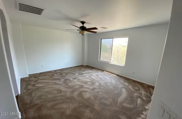 a view of a big room with windows and chandelier fan