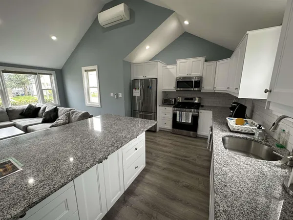 a large kitchen with stainless steel appliances granite countertop a stove refrigerator and a sink