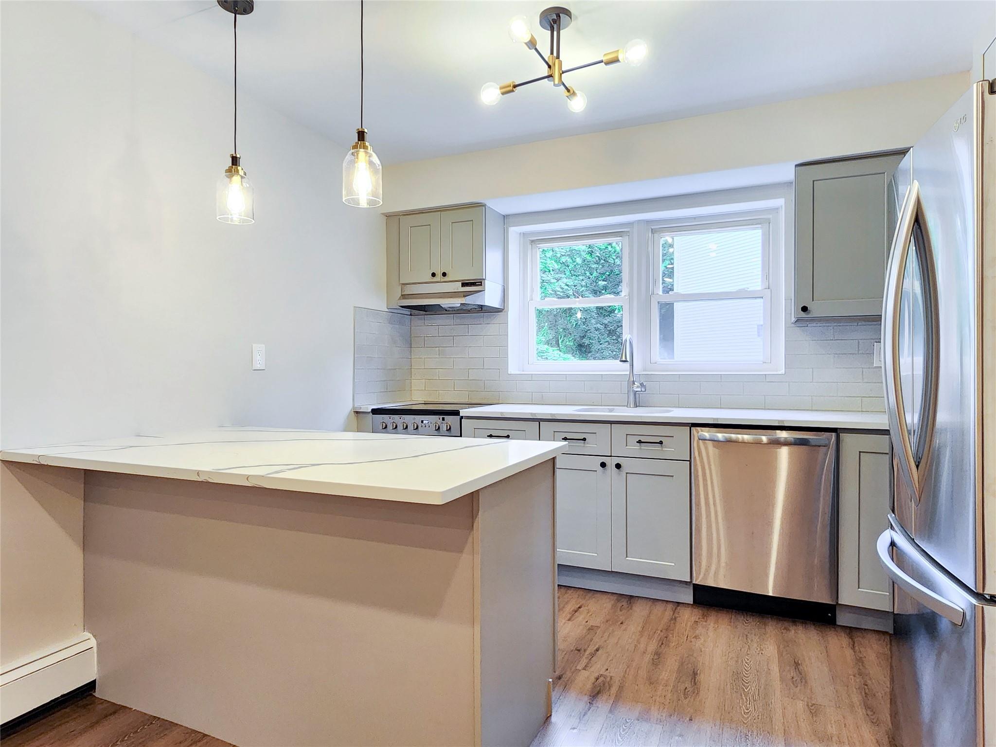 a kitchen with stainless steel appliances granite countertop a sink a stove a refrigerator and island with wooden floor