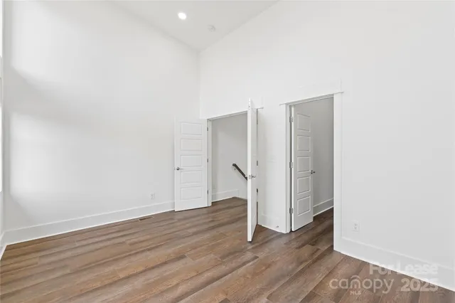 a view of an empty room with wooden floor and closet