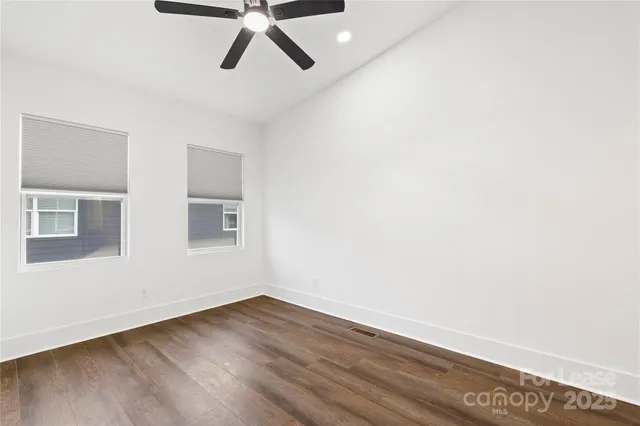 a view of an empty room with wooden floor and window