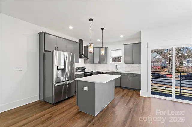 a kitchen with stainless steel appliances a refrigerator a stove and wooden floor