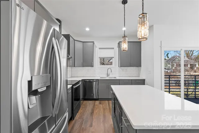 a large kitchen with a sink a counter space cabinets and stainless steel appliances