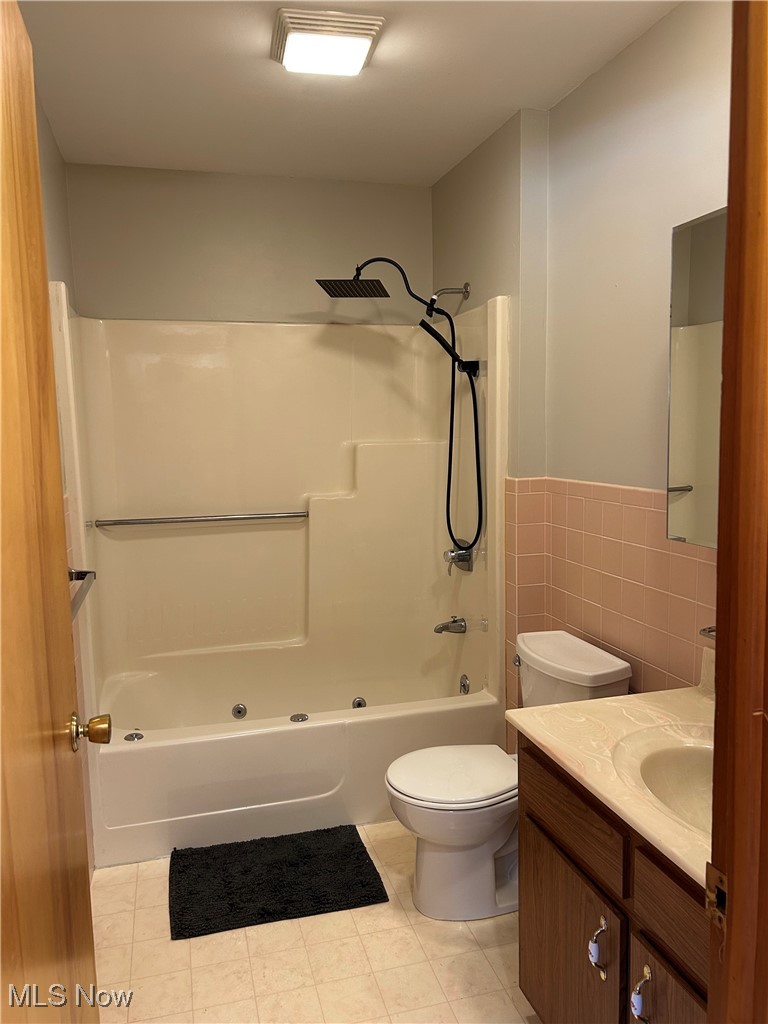 522 State Road Northwest Warren, OH 44483 - Photo 11 of 29 Bathroom featuring tile walls, vanity, washtub / shower combination, light tile patterned floors, and wainscoting