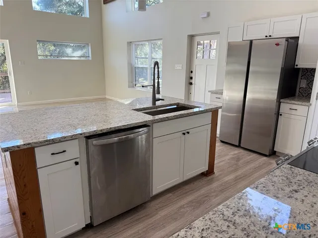a kitchen with stainless steel appliances granite countertop a sink a refrigerator and wooden floor