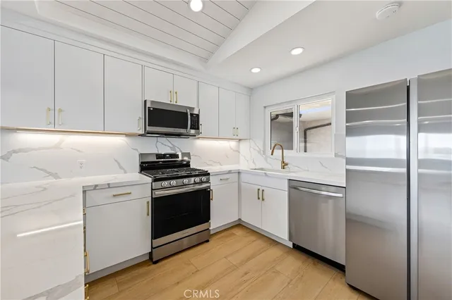a kitchen with cabinets stainless steel appliances and wooden floor