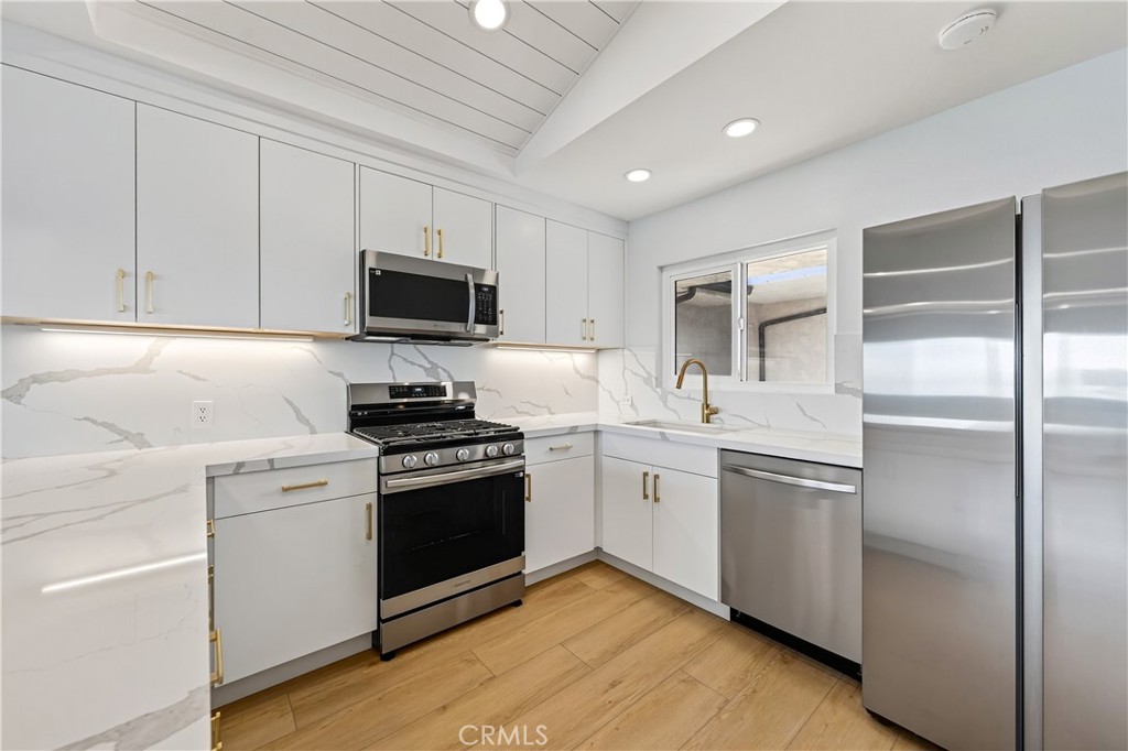 a kitchen with cabinets stainless steel appliances and wooden floor