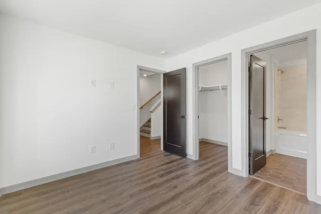 a view of an empty room with wooden floor and closet