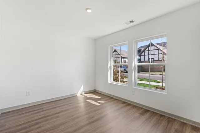 a view of an empty room with wooden floor and closet