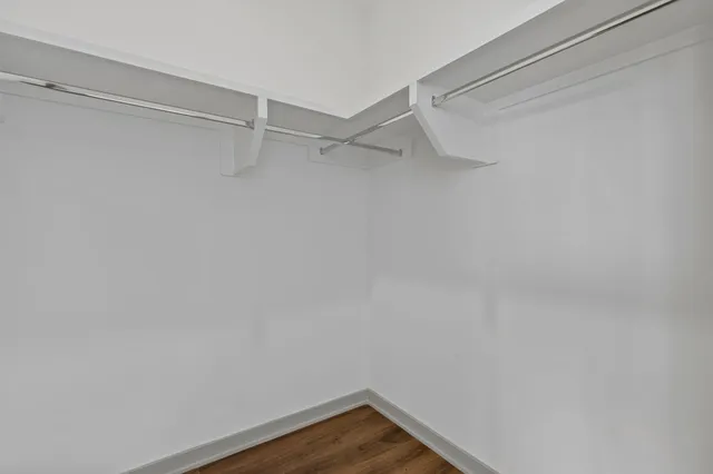 a view of an empty room with wooden floor & closet area