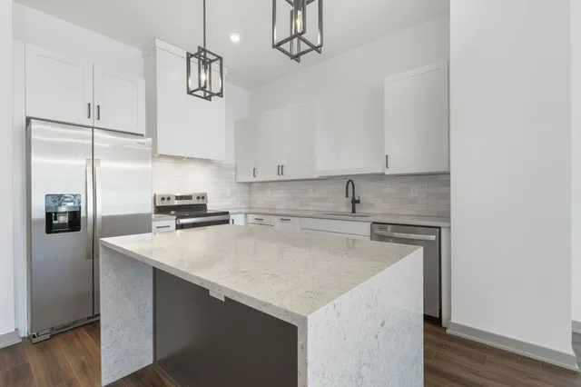 a kitchen with stainless steel appliances a sink a refrigerator a stove a microwave and cabinets