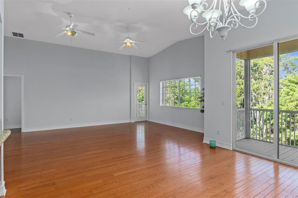 8229 Gulf Way Hudson, FL 34667 - Photo 12 of 35 an empty room with wooden floor chandelier fan and windows