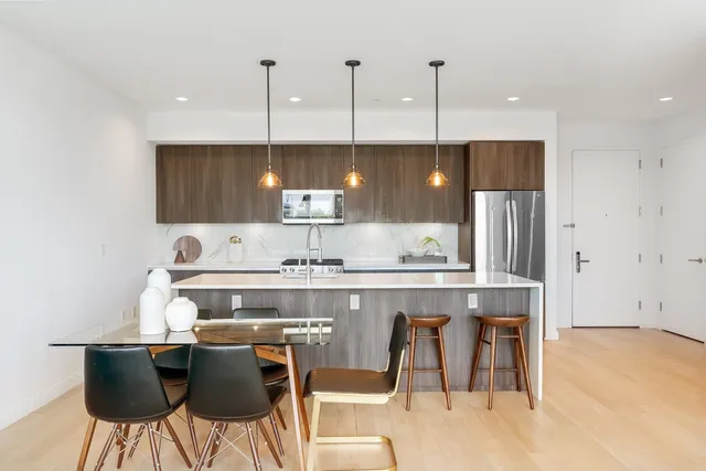 a kitchen with stainless steel appliances granite countertop a sink a stove a refrigerator and island with wooden floor