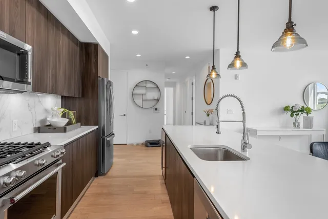 a kitchen with stainless steel appliances granite countertop a sink a stove and a refrigerator