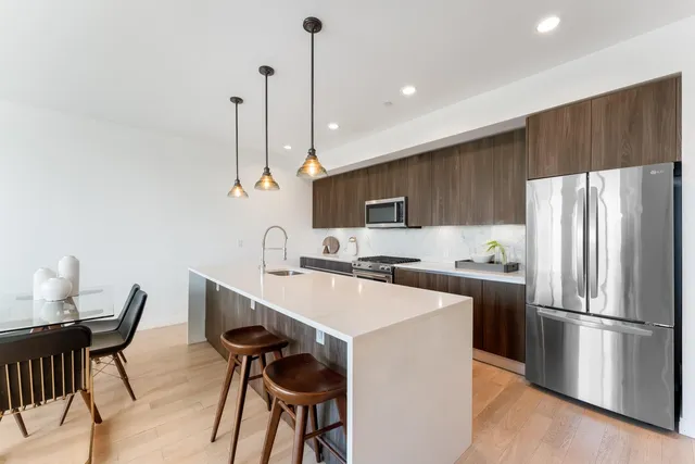 a kitchen with stainless steel appliances a dining table chairs refrigerator and sink