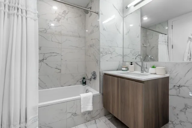 a bathroom with a bathtub shower sink and mirror