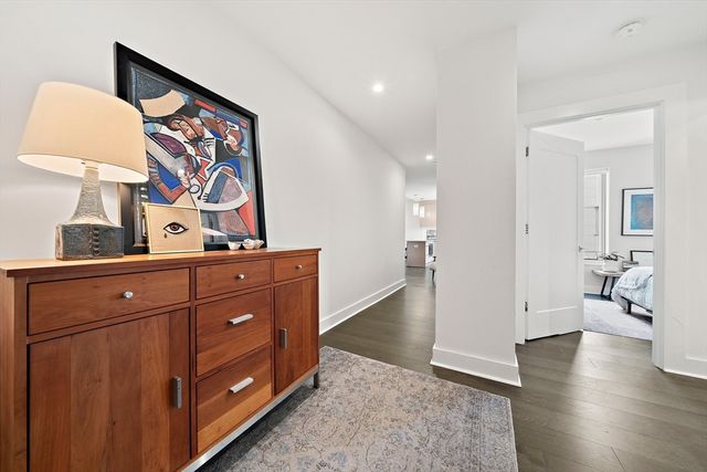 a view of a hallway with wooden floor and cabinet