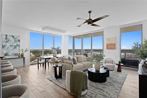 a living room with furniture a flat screen tv and a floor to ceiling window
