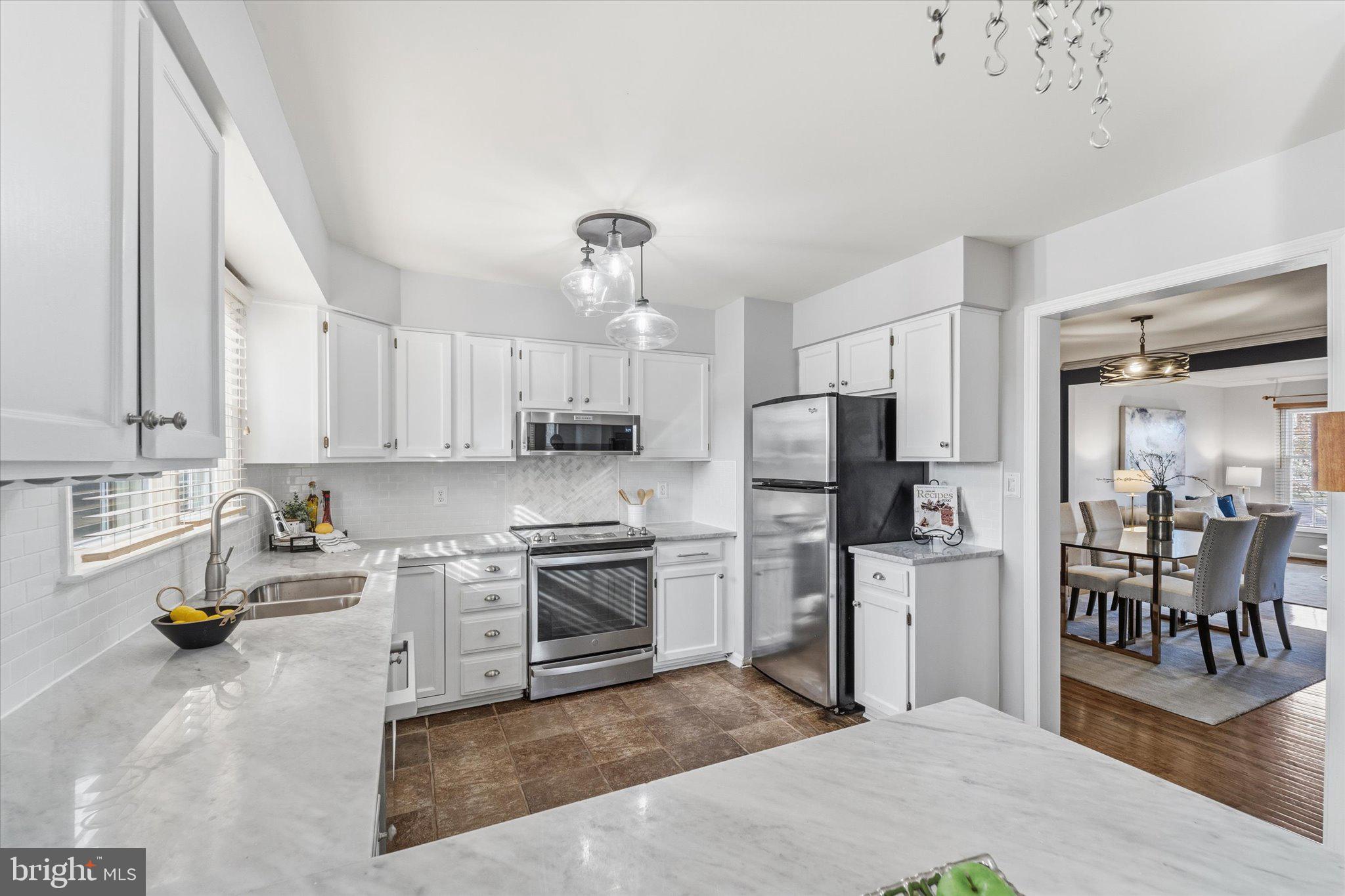 43451 Livery Square Ashburn, VA 20147 - Photo 11 of 51 a kitchen with stainless steel appliances kitchen island granite countertop a refrigerator oven stove a sink a dining table and chairs with wooden floor