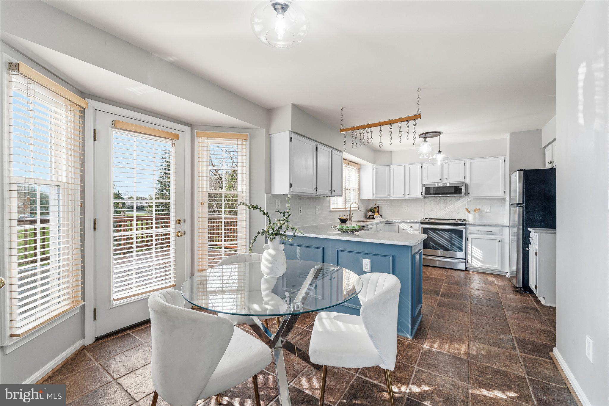 43451 Livery Square Ashburn, VA 20147 - Photo 15 of 51 a kitchen with kitchen island granite countertop a table chairs microwave and cabinets