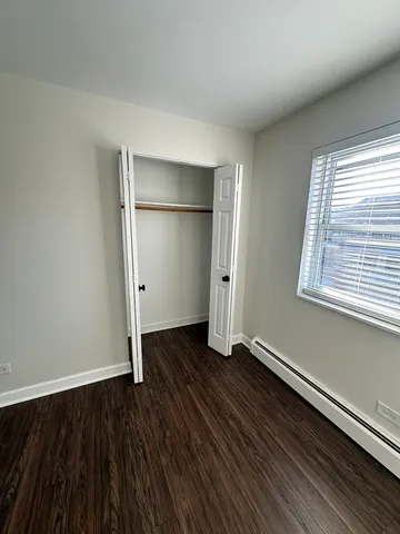 an empty room with wooden floor closet and windows