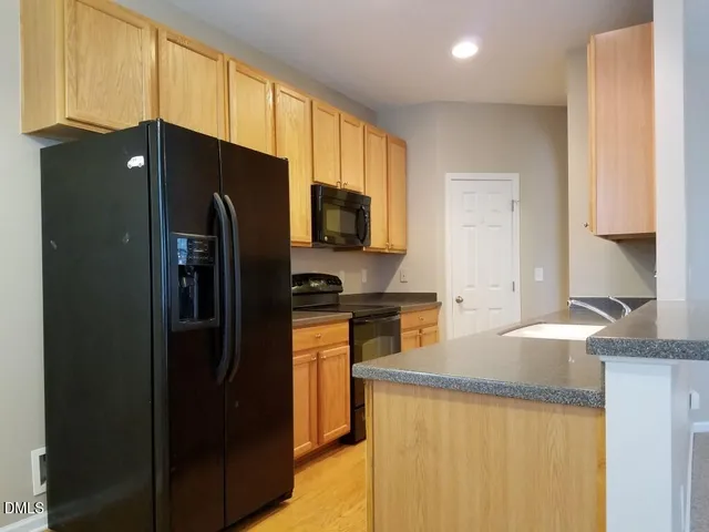 a kitchen with granite countertop a refrigerator stove and sink