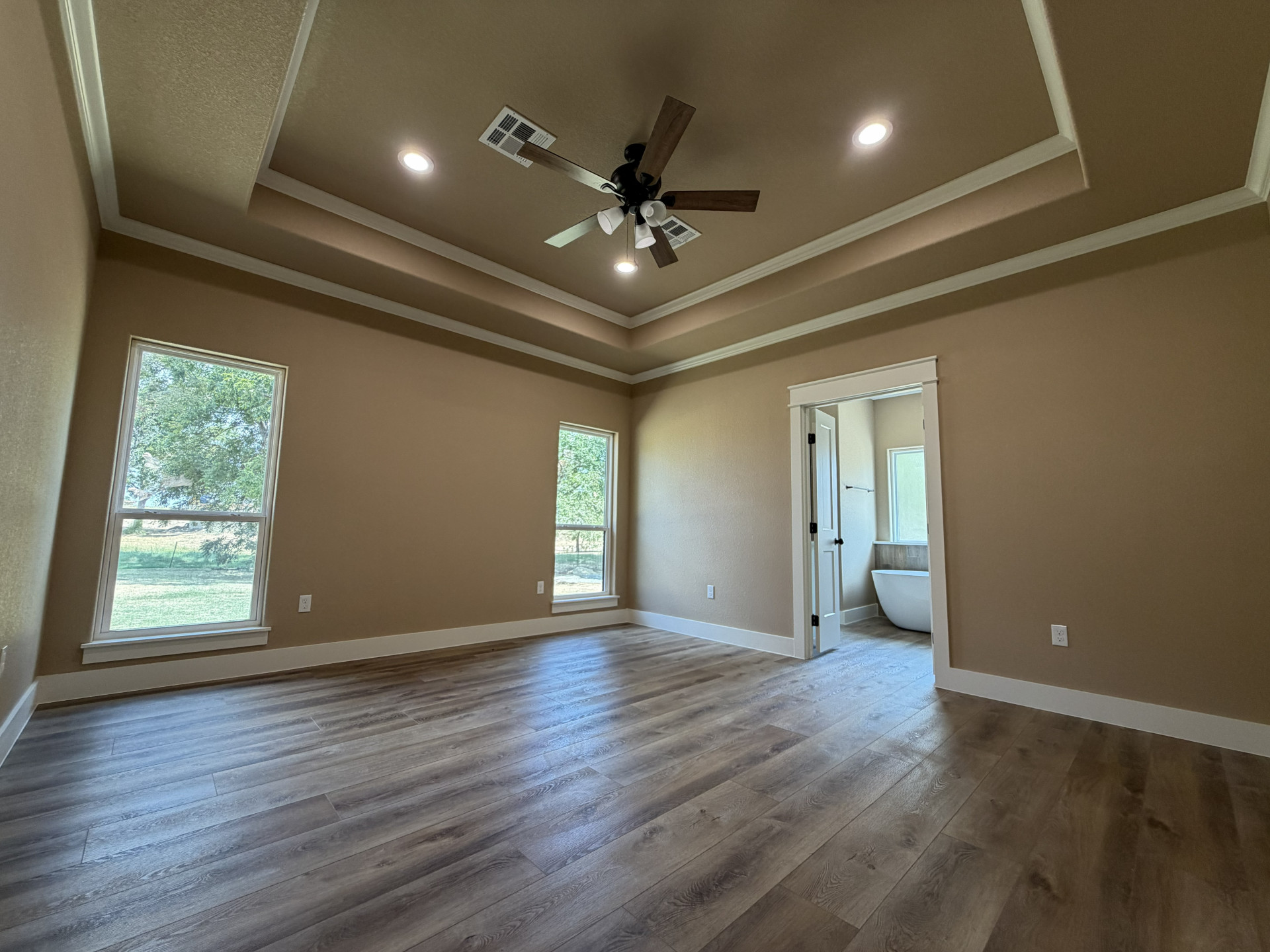 33 Wilderness Road North Calera, OK 74730 - Photo 8 of 39 Wood-finish flooring, recessed lighting, ceiling fan, two windows, and a tray ceiling with crown molding