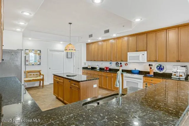 a kitchen with stainless steel appliances granite countertop a refrigerator a sink a stove and oven