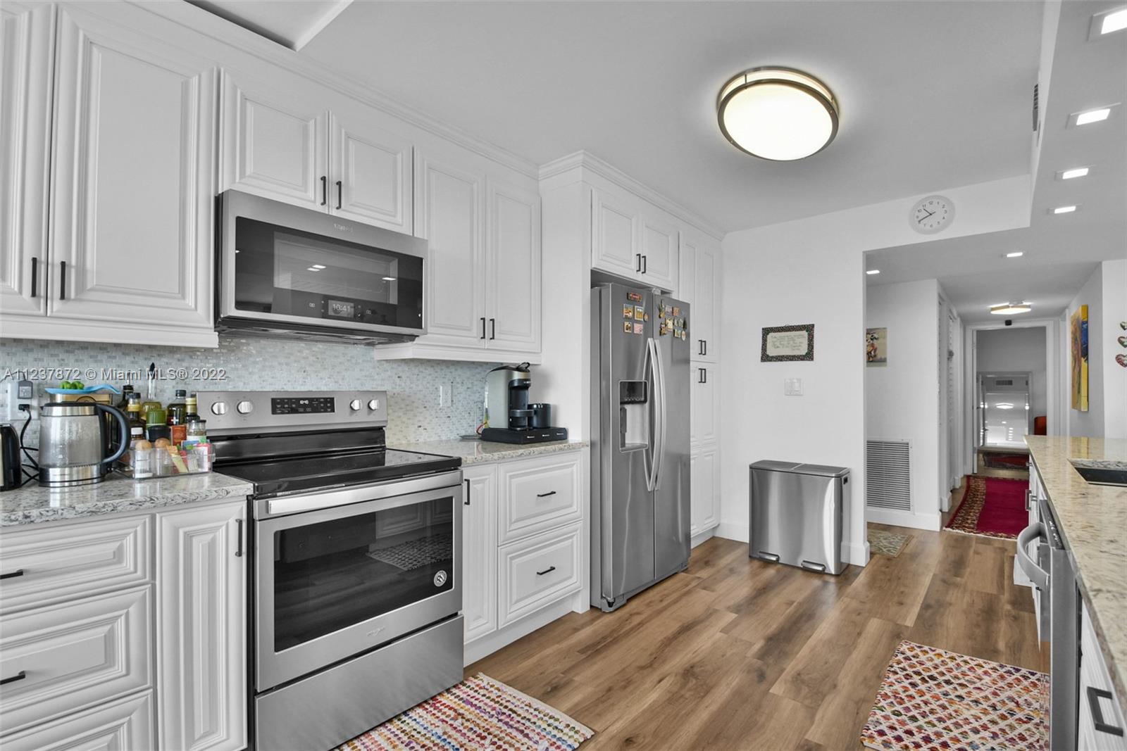 South Central Beach Hollywood, FL 33019 - Photo 23 of 30 a kitchen with stainless steel appliances granite countertop a stove a sink dishwasher and a refrigerator with wooden cabinets