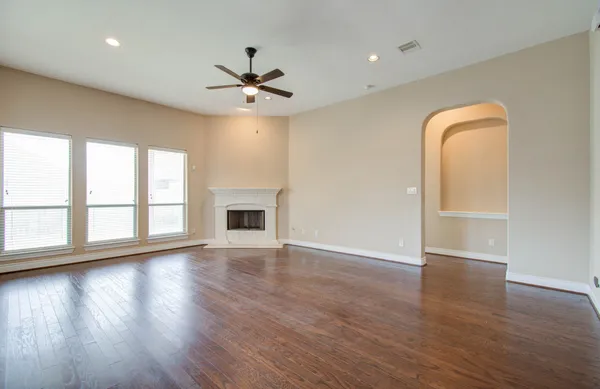 a view of an empty room with wooden floor and a window