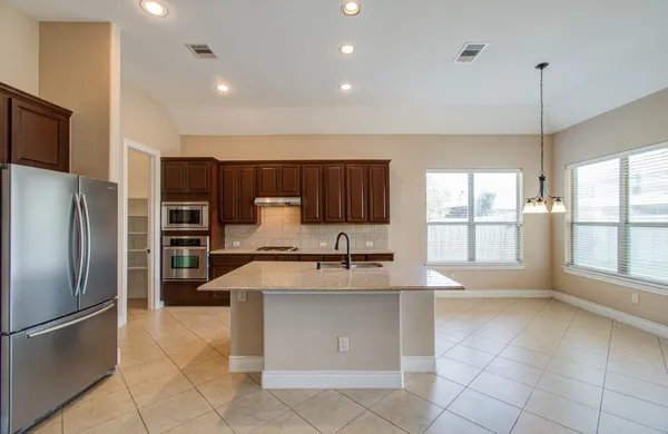 a large kitchen with kitchen island a large counter top stainless steel appliances and cabinets