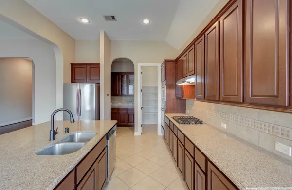 a kitchen with kitchen island granite countertop a sink and refrigerator