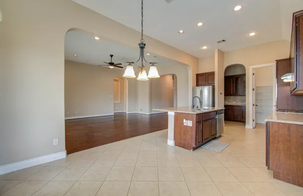 a large kitchen with stainless steel appliances a large counter top and a refrigerator