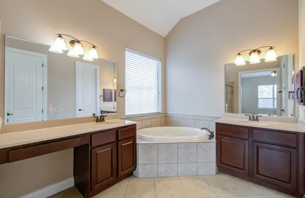 a bathroom with a sink double vanity mirror and a bathtub