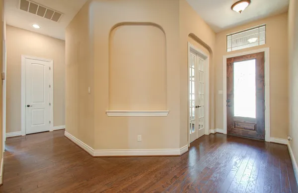 an empty room with wooden floor and windows