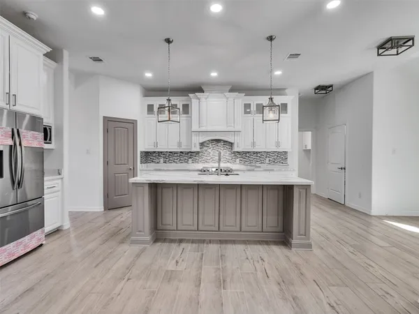 a kitchen with kitchen island wooden floors appliances and cabinets