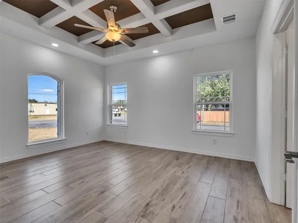 an empty room with wooden floor chandelier fan and windows