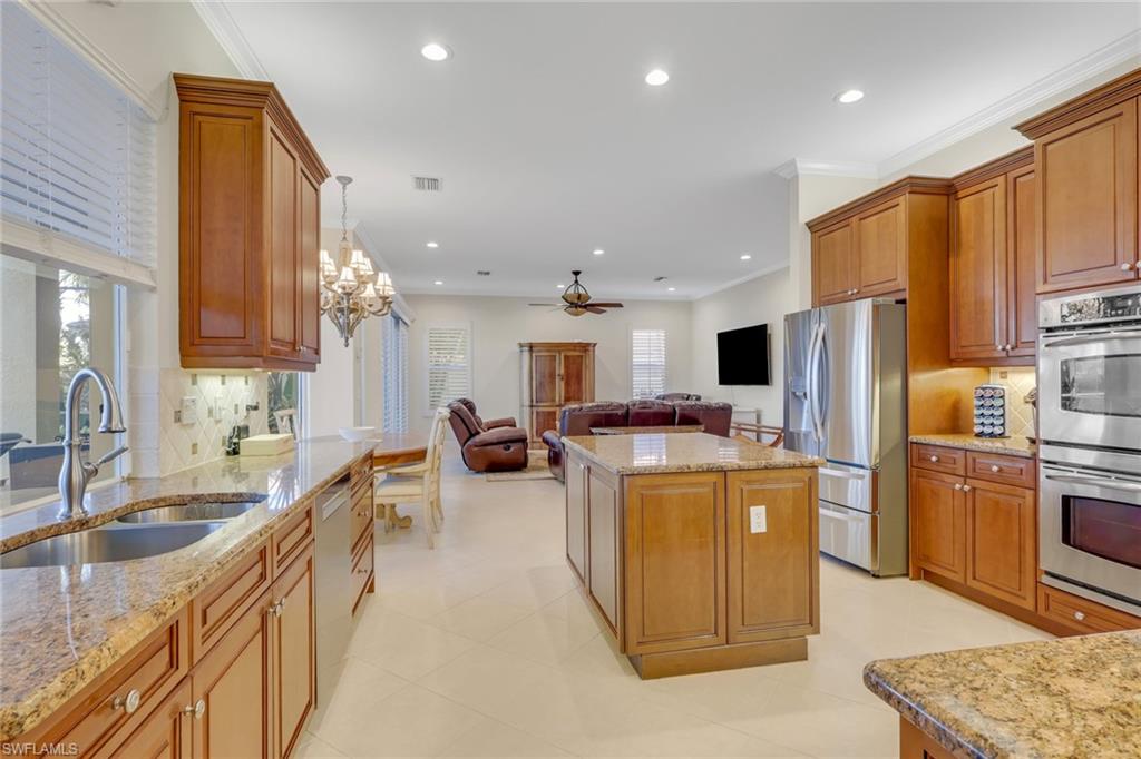1859 Ivory Cane Point Naples, FL 34119 - Photo 50 of 50 Kitchen featuring decorative backsplash, open floor plan, appliances with stainless steel finishes, brown cabinets, and crown molding