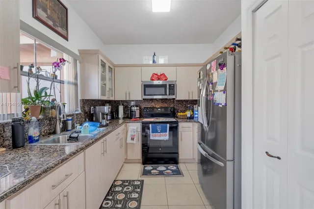 a kitchen with stainless steel appliances granite countertop a sink and a refrigerator