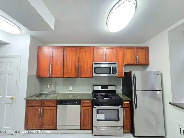 a kitchen with stainless steel appliances granite countertop a stove a refrigerator and a microwave