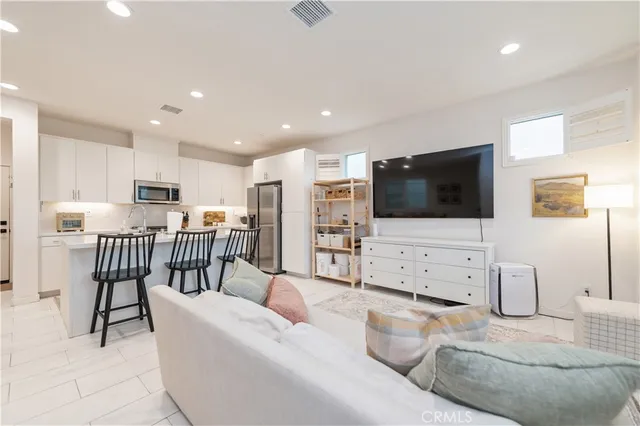 a kitchen with stainless steel appliances a dining table chairs and a refrigerator