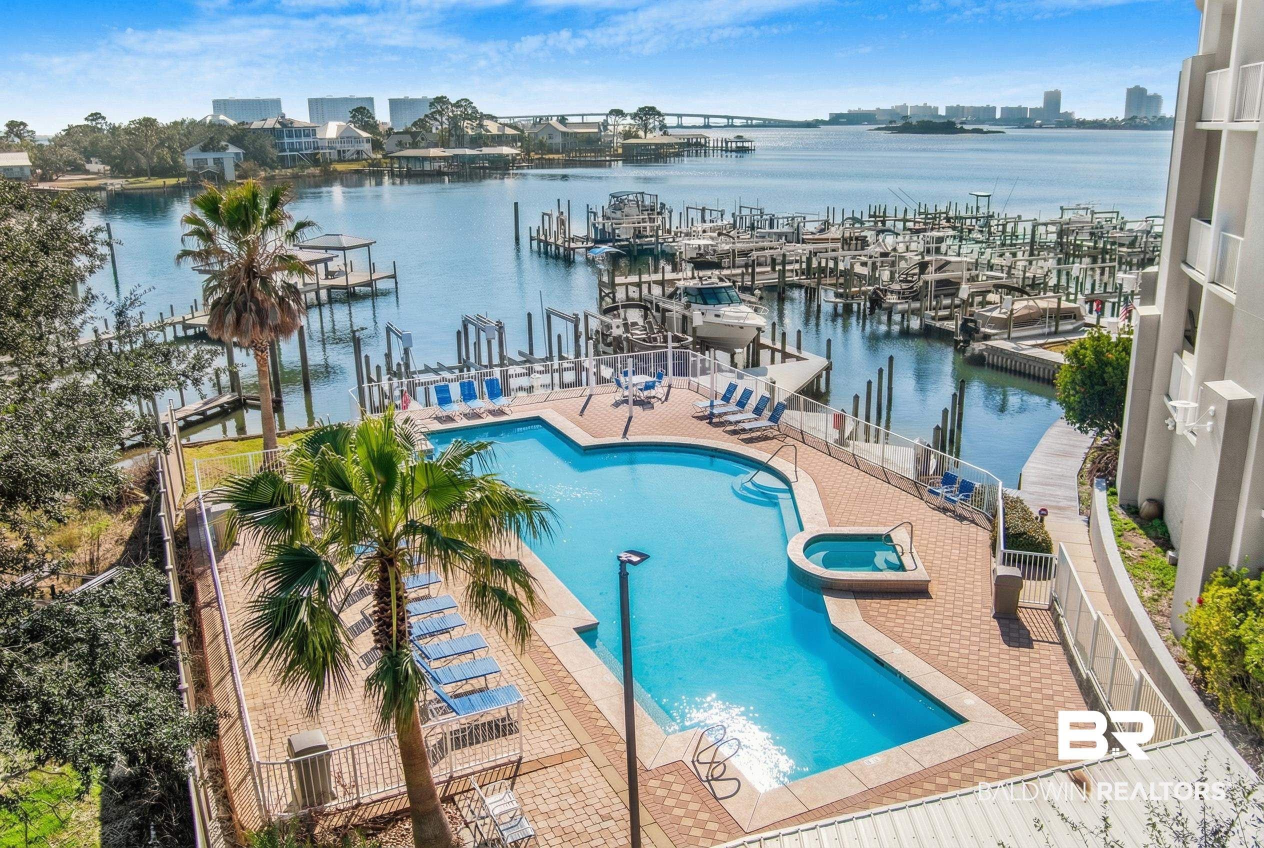 28250 Canal Road, Unit 106 Orange Beach, AL 36561 - Photo 32 of 50 View of pool featuring a water view, a pool with connected hot tub, view of marina, and a patio area