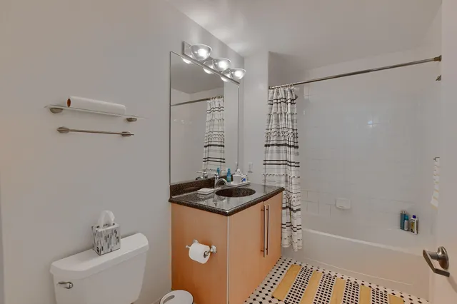 a bathroom with a granite countertop sink a toilet a shower and a mirror
