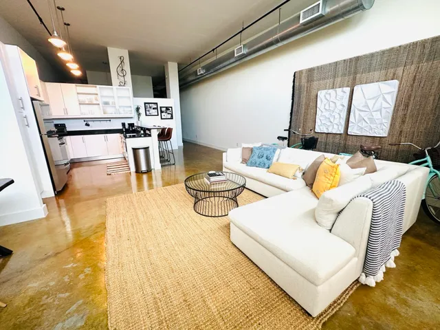 a living room with stainless steel appliances furniture and a table