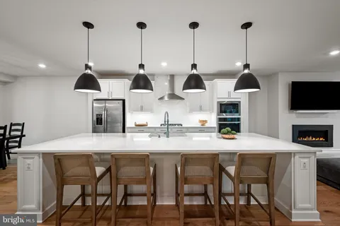a kitchen with stainless steel appliances kitchen island granite countertop a dining table chairs and white cabinets