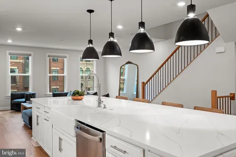 a kitchen with stainless steel appliances a sink a chandelier and living room view