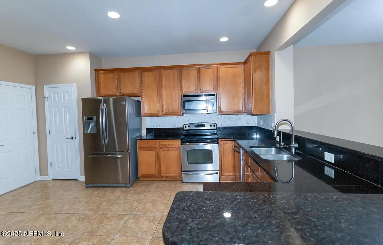 4204 Metron Drive Jacksonville, FL 32216 - Photo 6 of 24 a kitchen with stainless steel appliances granite countertop a refrigerator a stove a sink and a microwave